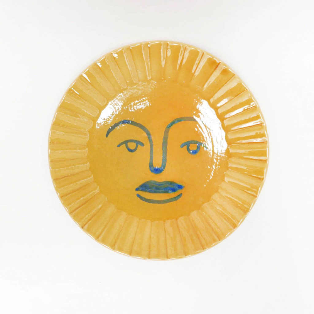 Plat de service rond jaune oranger en forme de soleil et motif visage bleu foncé peint à l'intérieur